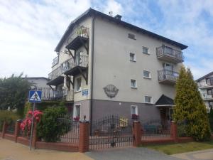 a large white building with balconies and a fence at Wędrowiec in Karwia