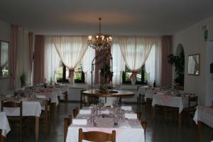 a dining room with tables and chairs and a chandelier at Hotel Milano in Folgaria
