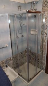 a shower with a glass door next to a toilet at Serenella Apartament in San Vito lo Capo