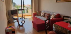 - un salon avec un canapé rouge et une télévision dans l'établissement Apartment on The Strip Albufeira, à Albufeira