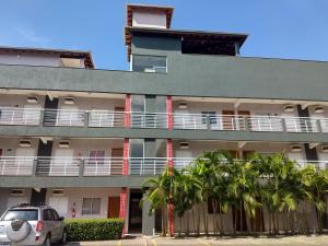 an apartment building with palm trees in front of it at Apartamento Ubatuba-SP -Itaguá in Ubatuba