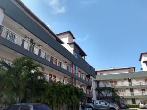 an apartment building with cars parked in front of it at Apartamento Ubatuba-SP -Itaguá in Ubatuba
