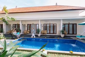a villa with a swimming pool in front of a house at Kubu Benoa Guest House in Nusa Dua