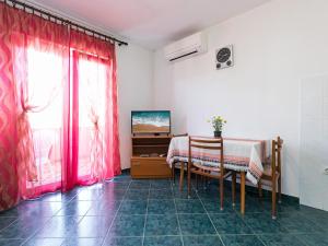 Zimmer mit einem Tisch, einem TV und roten Vorhängen in der Unterkunft Apartment Nerina in Poreč