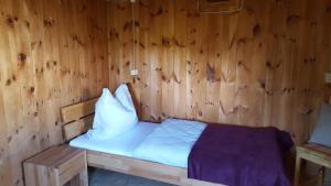 a wooden room with a bed with white sheets and pillows at Kloiberhof in Öblarn
