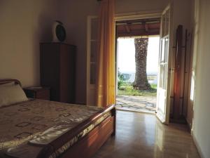 Schlafzimmer mit einem Bett und einer Tür zu einer Terrasse in der Unterkunft APARTMENTS PELI-MARIA in Agios Stefanos