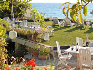 un jardín con sillas blancas, una mesa y el océano en Palmina Mare Villa and Studios, en Paralia Vrachou