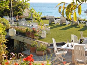 a garden with white chairs and a table and the ocean at Palmina Mare Villa and Studios in Paralia Vrachou