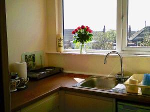 a kitchen with a sink and a window with a vase of flowers at 24 Elmhurst Road in Lytham St Annes