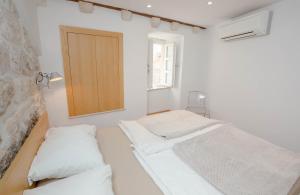 two beds in a white room with a window at Apartment Sorta in Dubrovnik