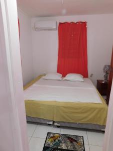 a small bedroom with a bed with a red curtain at ixora in Sainte-Anne