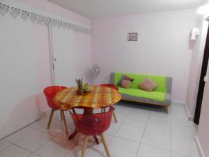 a living room with a table and a green couch at ixora in Sainte-Anne