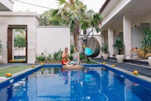 twee personen naast een zwembad bij Kubu Benoa Guest House in Nusa Dua