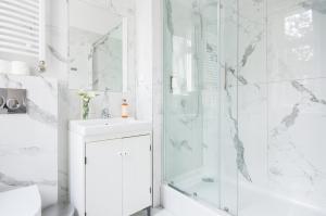 a white bathroom with a shower and a sink at Riviera Residence Apartments in Sopot