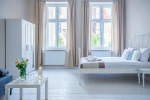 a white room with a bed and two windows at Riviera Residence Apartments in Sopot