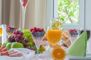 stół z dwoma kieliszkami soku pomarańczowego i owoców w obiekcie Riviera Residence Apartments w mieście Sopot