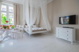 Biały pokój z łóżeczkiem dziecięcym i stołem z krzesłami w obiekcie Riviera Residence Apartments w mieście Sopot