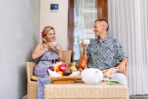 a man and a woman sitting in a chair eating food at Kubu Benoa Guest House in Nusa Dua