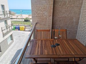 een houten tafel en stoelen op een balkon met uitzicht op de oceaan bij Apartamento Sweet Home in Malgrat de Mar