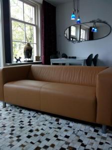 a brown couch in a living room with a window at Jordaan Canal View Apartment in Amsterdam