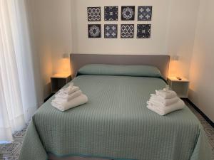 a bedroom with a green bed with towels on it at Angelina Apartments Amalfi Coast in Maiori