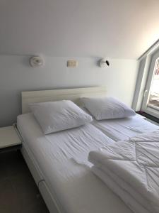 a white bed with two pillows and a window at Residentie Kapelhof in Koksijde
