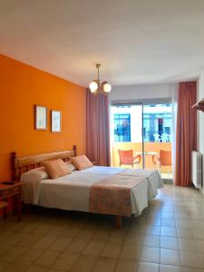 1 dormitorio con 1 cama con pared de color naranja en Apartamentos Jovial en San Antonio