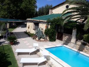 a swimming pool with two white chairs and a house at Casa Del Leone Rosso e Welness a due passi dalla Costa dei Trabocchi in San Vito Chietino