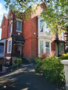 een rood bakstenen huis met een oprit ervoor bij Chimneys Guest House in Blackburn