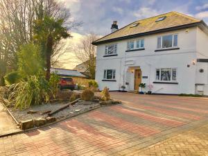 a white house with a brick driveway at TRETHEWEY GUEST HOUSE in Fowey