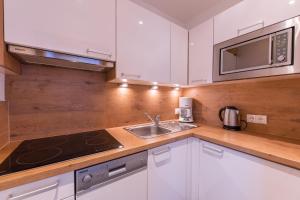 kuchnia z białymi szafkami, zlewem i kuchenką mikrofalową w obiekcie Appartement Holzknecht w Solden +16 zdjęć
