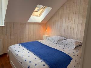 a bedroom with a bed with a blue blanket and a skylight at Clos des Ursulines in Bayeux