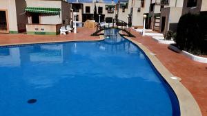 a large blue swimming pool with buildings in the background at Casa Playa Puerto Mazarrón in Puerto de Mazarrón