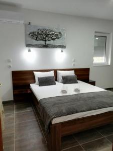 - une chambre avec un grand lit et un arbre sur le mur dans l'établissement Apartmani Nana Sokobanja, à Sokobanja