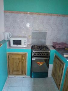 uma cozinha com um fogão e um micro-ondas em Chez Coumba et Daniel em Saly Portudal