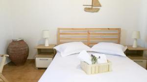 a white bed with two pillows and a box on it at Anemos Seaside House in Skiros