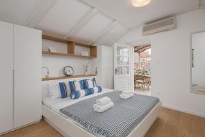a white bedroom with a large bed with blue pillows at Apartments Olaf in Dubrovnik