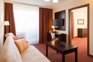 a hotel room with a couch and a table and a mirror at Hotel Ostrawa in Wodzisław Śląski