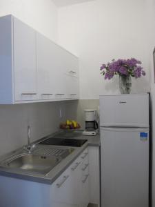 a white kitchen with a sink and a refrigerator at Haus Katerina in Vourvourou