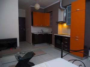 ラガナスにあるDolce Vita Apartmentのキッチン(オレンジ色のキャビネット、ガラスのテーブル付)