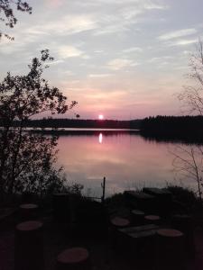 una puesta de sol sobre un lago con barcos en él en Ollilan Lomamajat, en Kuusamo