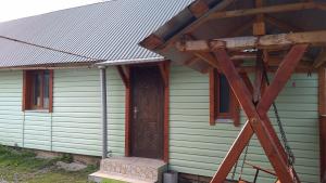 une maison verte avec une porte en bois et une terrasse couverte dans l'établissement Базилік Люкс, à Yaremtche