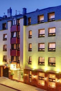 - un grand bâtiment blanc avec des fenêtres sur le côté dans l'établissement Hotel Granus, à Aix-la-Chapelle