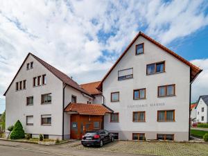 une maison blanche avec une voiture garée devant elle dans l'établissement Gästehaus Marion, à Dettingen an der Erms