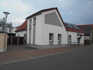 una casa blanca con techo rojo en una calle en Ferienapartment-Monteurwohnung-Muldestausee, en Pouch