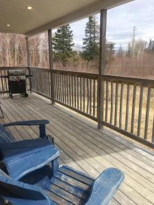 a porch with two blue rocking chairs on it at The Country Inn Cottage in Gander