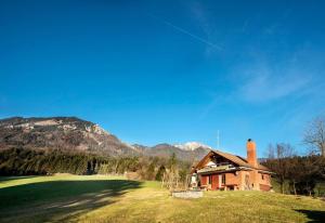 ein Haus auf einem grünen Feld mit Bergen im Hintergrund in der Unterkunft Little dream house in a perfect spot in Zalog