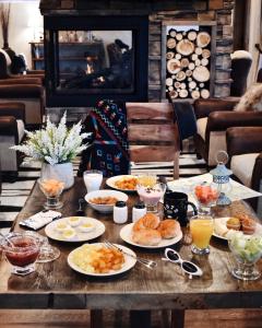 a table with plates of food on it with a fireplace at 1872 Inn - Adults Exclusive in West Yellowstone