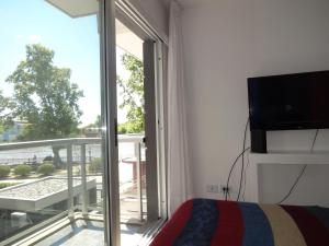 a bedroom with a bed and a balcony with a tv at Paseo Victorica al 700 in Tigre
