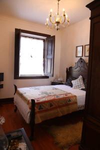 um quarto com uma cama com um lustre e uma janela em Quinta de Vila Verde- Paixão Ancestral, Turismo Rural em Marco de Canavezes